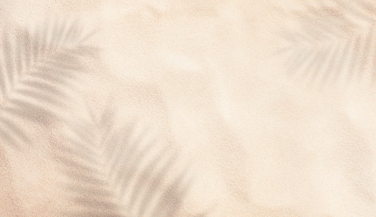 summer background of beach sand with shadows from palm leaves, top view