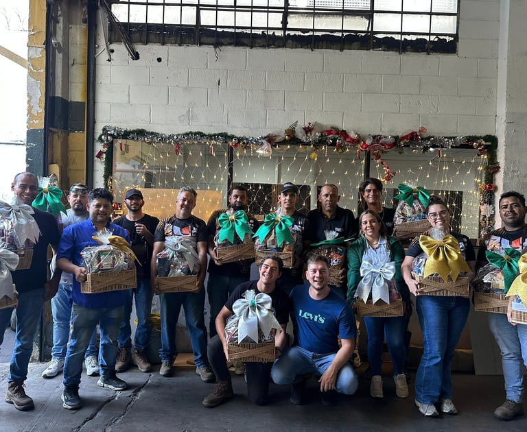 Group of volunteers holding food donation boxes in front of a decorated wall with garland and lights